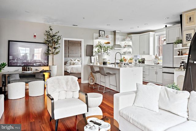 a kitchen with stainless steel appliances kitchen island granite countertop a stove a refrigerator a sink a dining table and chairs with wooden floor