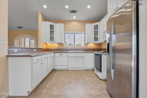 a kitchen with granite countertop a refrigerator and white cabinets