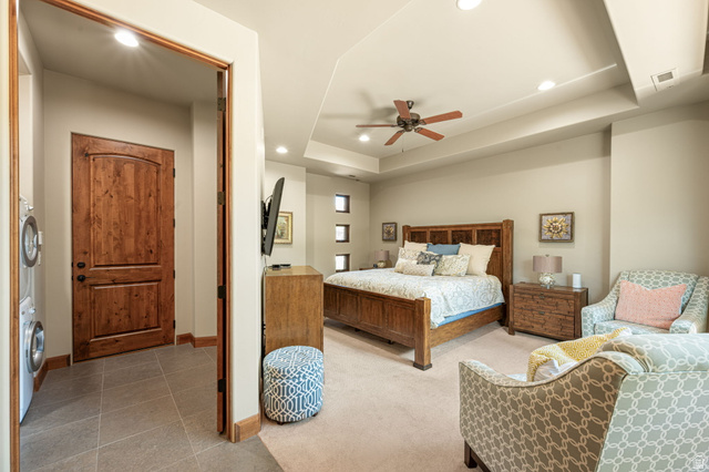 2331 West Entrada Trail, Unit 61 St. George, UT 84770 - Photo 50 of 69 Bedroom featuring a tray ceiling with recessed lighting and a ceiling fan, carpet flooring, and a doorway opening to a utility area with stacked appliances and tile flooring