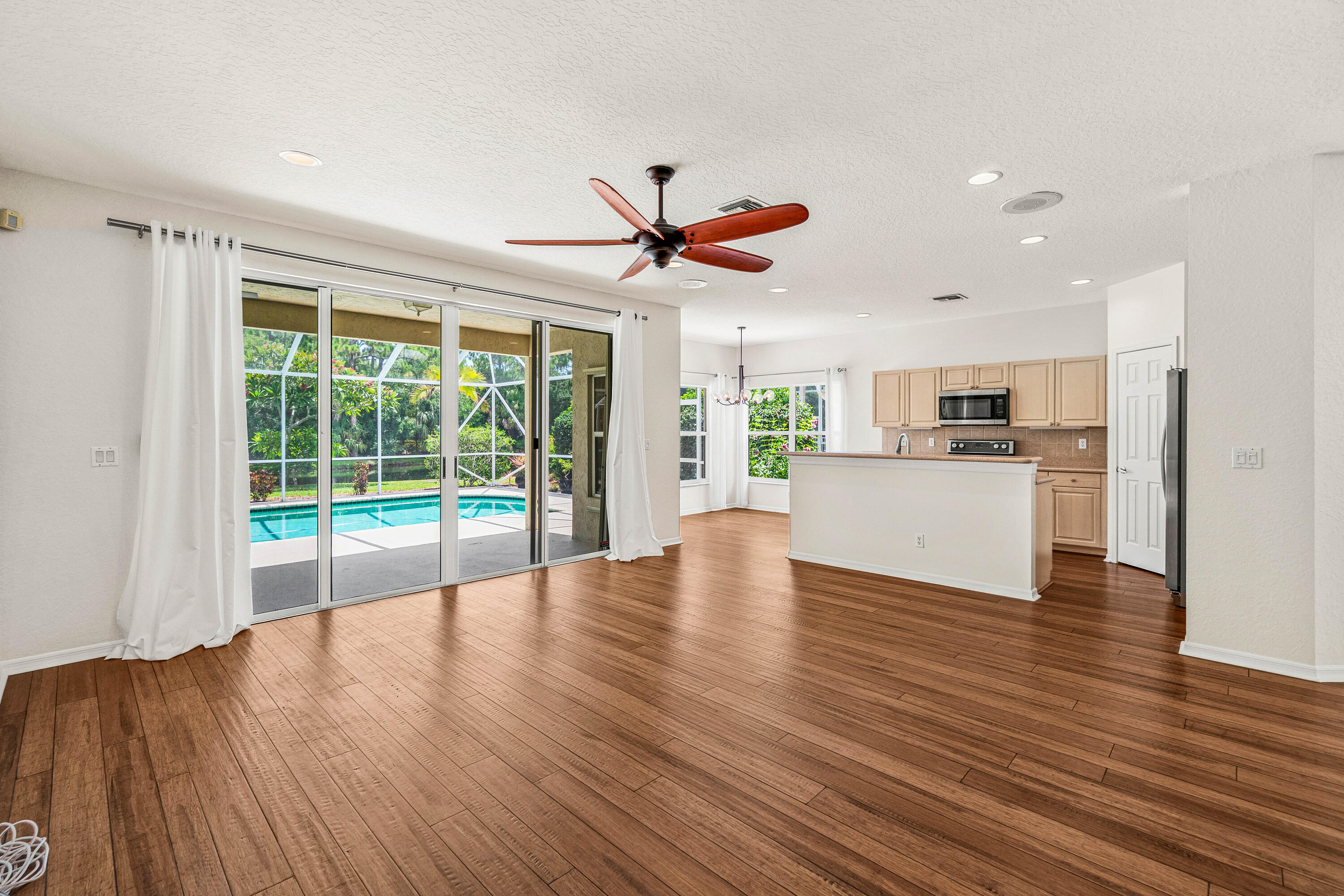 207 Pennock Trace Drive Jupiter, FL 33458 - Photo 6 of 48 a view of a living room and kitchen with furniture wooden floor and a ceiling fan
