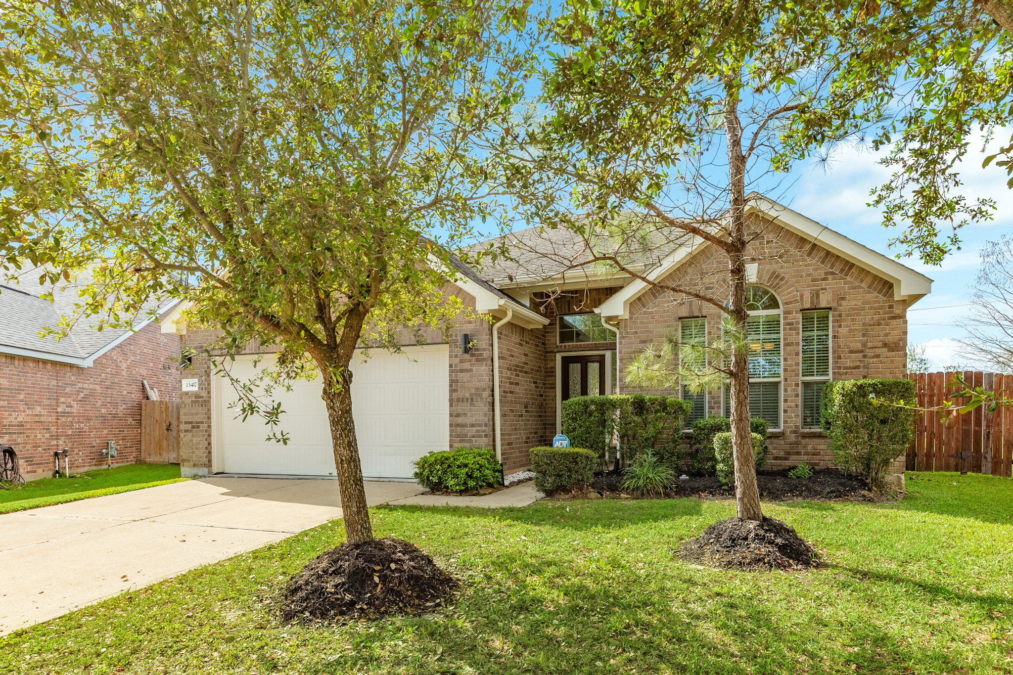 13417 Star Creek Lane Rosharon, TX 77583 - Photo 40 of 41 This photo captures the inviting front of the property, showcasing mature shade trees and beautifully maintained landscaping, including vibrant flower beds.
