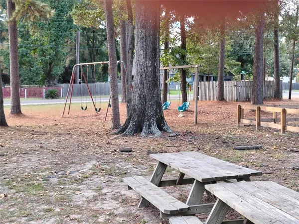 a view of a backyard with a slide trees and wooden fence