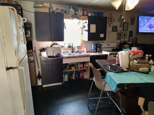 a kitchen with stainless steel appliances a stove a refrigerator a sink a dining table and chairs