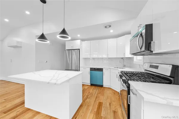 a kitchen with stainless steel appliances granite countertop a sink a stove a refrigerator and island with wooden floor