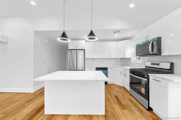 a kitchen with stainless steel appliances a stove a sink a refrigerator a center island and cabinets