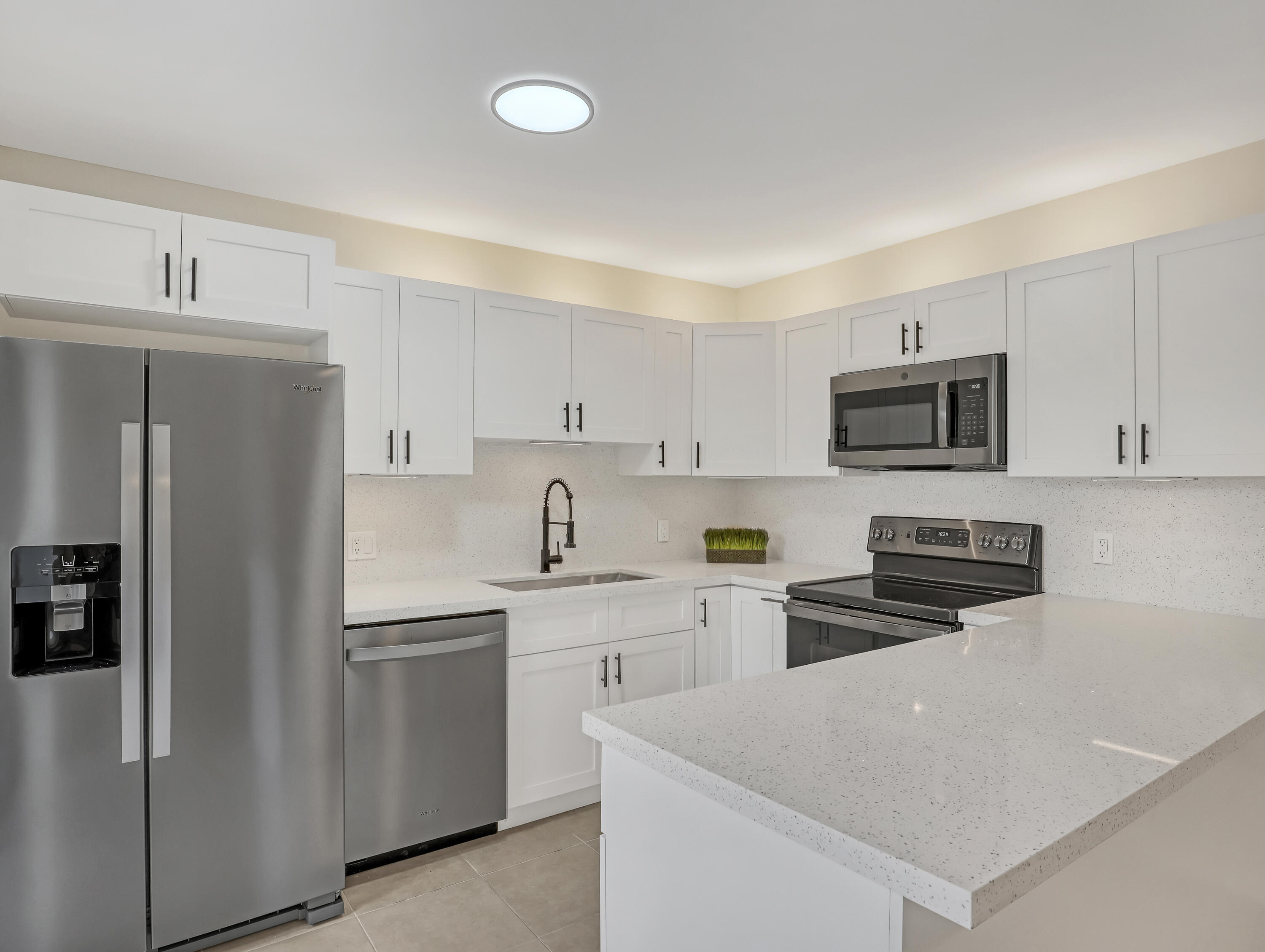 5738 Southeast Windsong Lane, Unit 315 Stuart, FL 34997 - Photo 13 of 32 a kitchen with white cabinets and stainless steel appliances