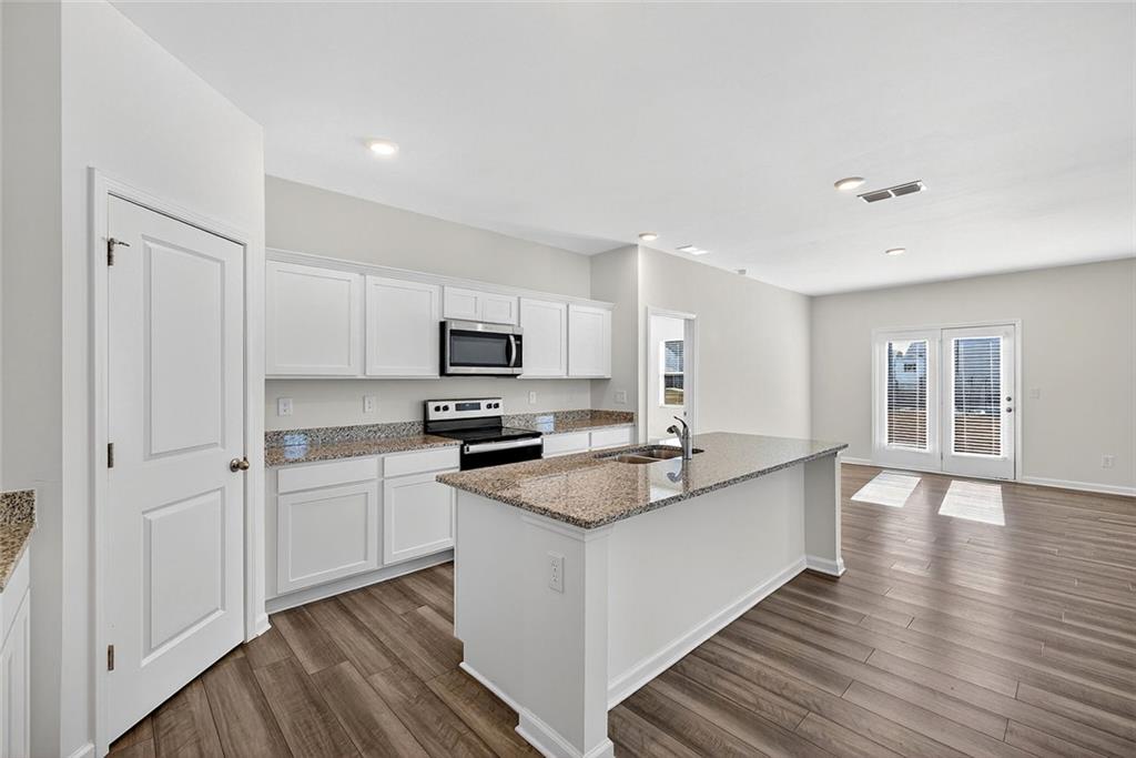 214 Georgian Way Locust Grove, GA 30248 - Photo 8 of 31 a kitchen with stainless steel appliances granite countertop a sink stove and refrigerator