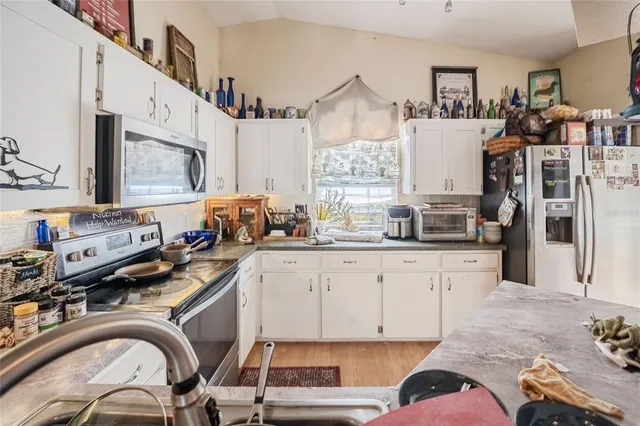 a kitchen with stainless steel appliances a sink a stove a refrigerator cabinets and a dining table