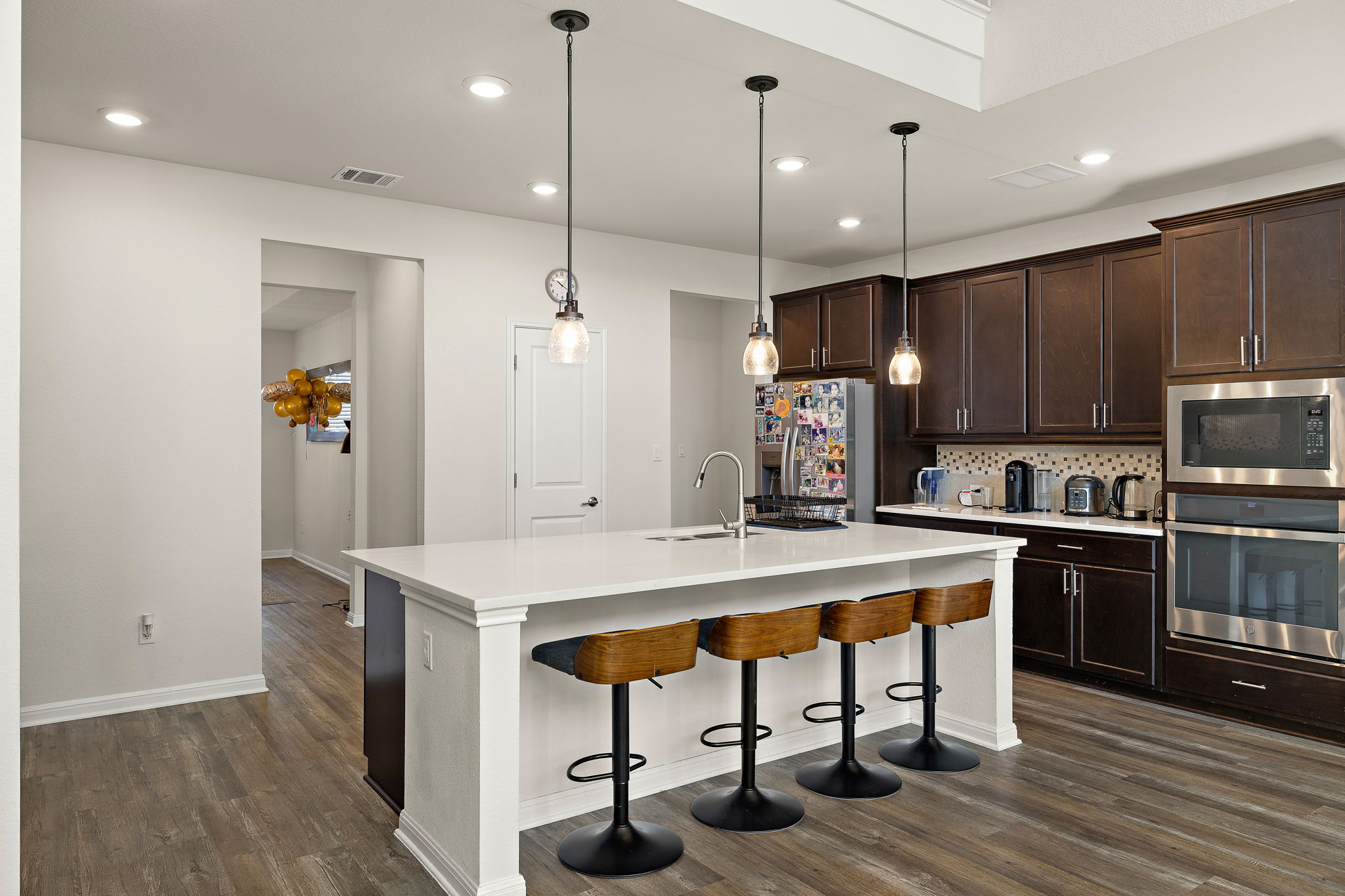 604 Spindrift Lane Leander, TX 78641 - Photo 7 of 32 Kitchen with a breakfast bar, stainless steel appliances, dark wood finish cabinetry, a center island with sink, and decorative backsplash