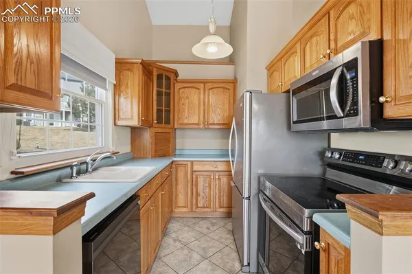a kitchen with stainless steel appliances granite countertop a sink a stove a refrigerator cabinets and a dining table