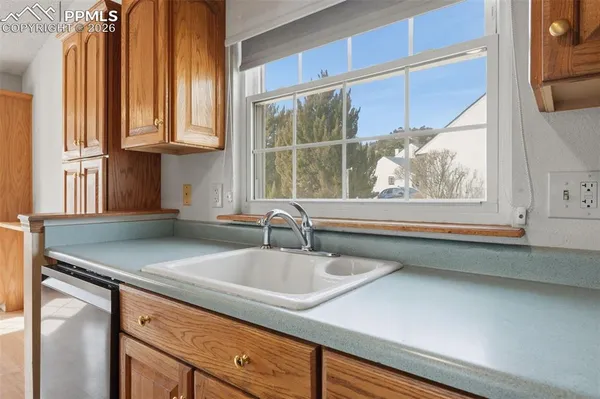 a kitchen with granite countertop a sink a window and cabinets