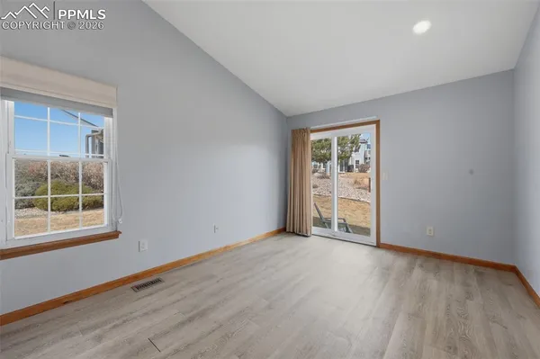 a view of an empty room with wooden floor and a window