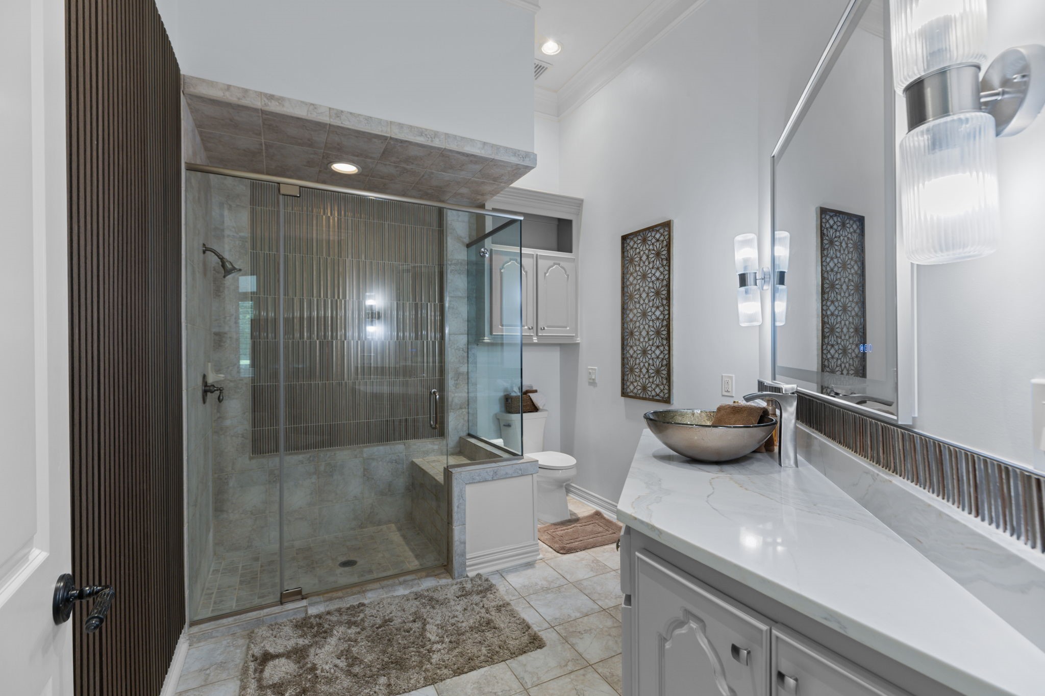 39 Maymont Way Spring, TX 77382 - Photo 18 of 50 This bathroom features a modern design with a spacious glass-enclosed shower, elegant tile flooring, and a sleek vanity with a contemporary vessel sink. Bright lighting and stylish decor add a touch of luxury.