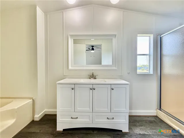 a bathroom with a sink vanity tub and a mirror