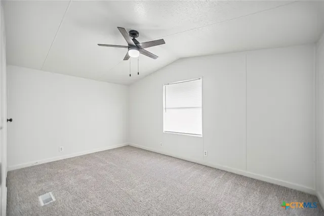 an empty room with a window and a fan