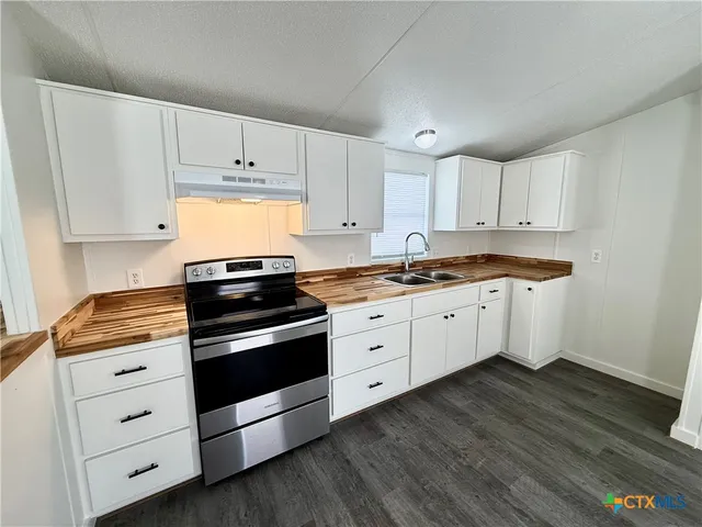a kitchen with granite countertop white cabinets and white appliances