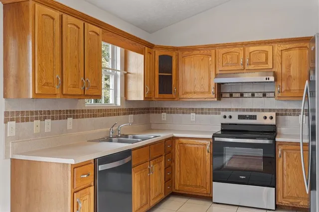 a kitchen with stainless steel appliances granite countertop a stove a sink and a microwave