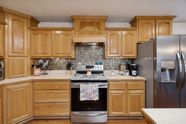 a kitchen with stainless steel appliances granite countertop a sink dishwasher stove refrigerator and cabinets