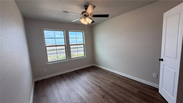 a view of an empty room with wooden floor and a window