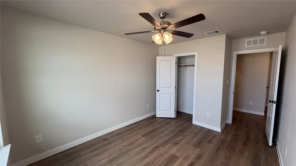 an empty room with wooden floor and a ceiling fan