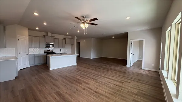 a view of kitchen with kitchen island wooden floors appliances and cabinets