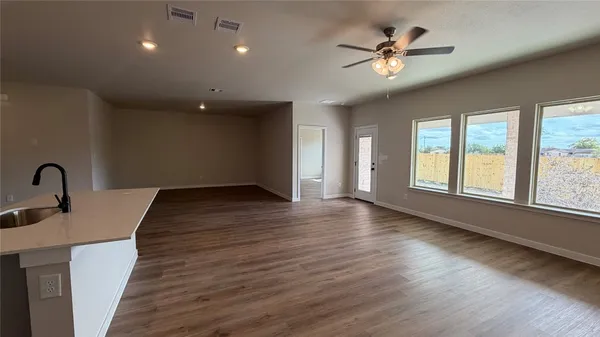 a view of an empty room with a window and wooden floor