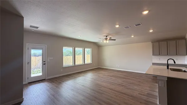 an empty room with wooden floor and windows