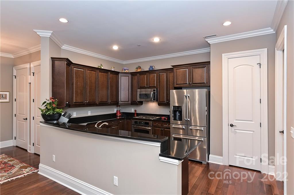 3240 Park Road Charlotte, NC 28209 - Photo 7 of 39 a kitchen with kitchen island granite countertop a stove a refrigerator and a sink with wooden floor