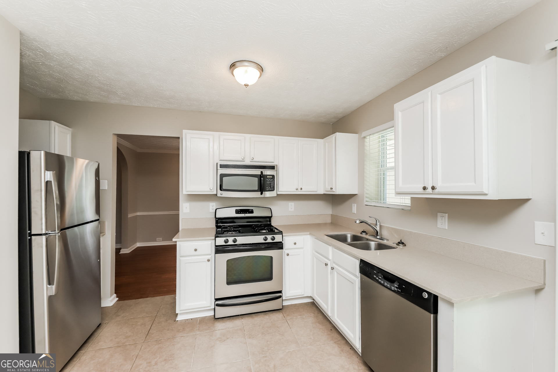 9945 Rivercliff Lane Villa Rica, GA 30180 - Photo 7 of 17 a kitchen with stainless steel appliances a refrigerator sink and white cabinets