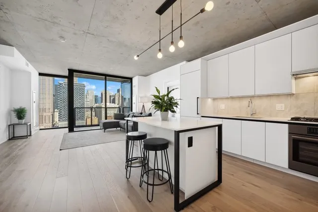 a kitchen with stainless steel appliances granite countertop a stove a sink a refrigerator and white cabinets with wooden floor