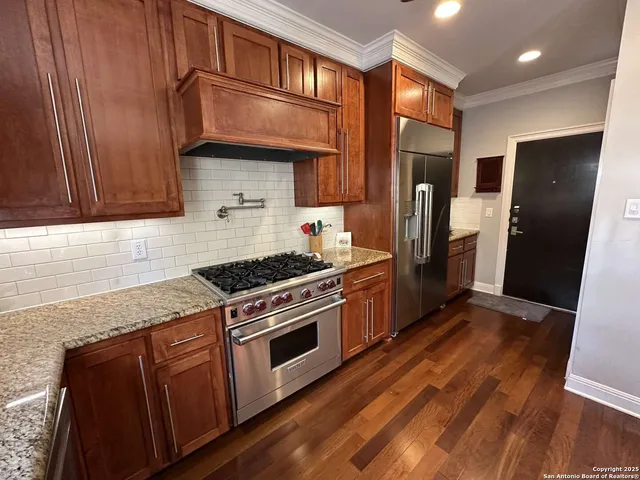 a kitchen with stainless steel appliances granite countertop a refrigerator a stove and a sink