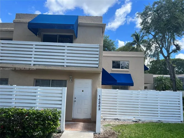 a view of a white house with a small yard and large tree