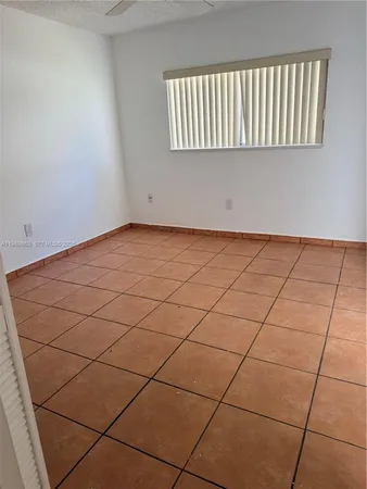 an empty room with wooden floor and windows with curtains