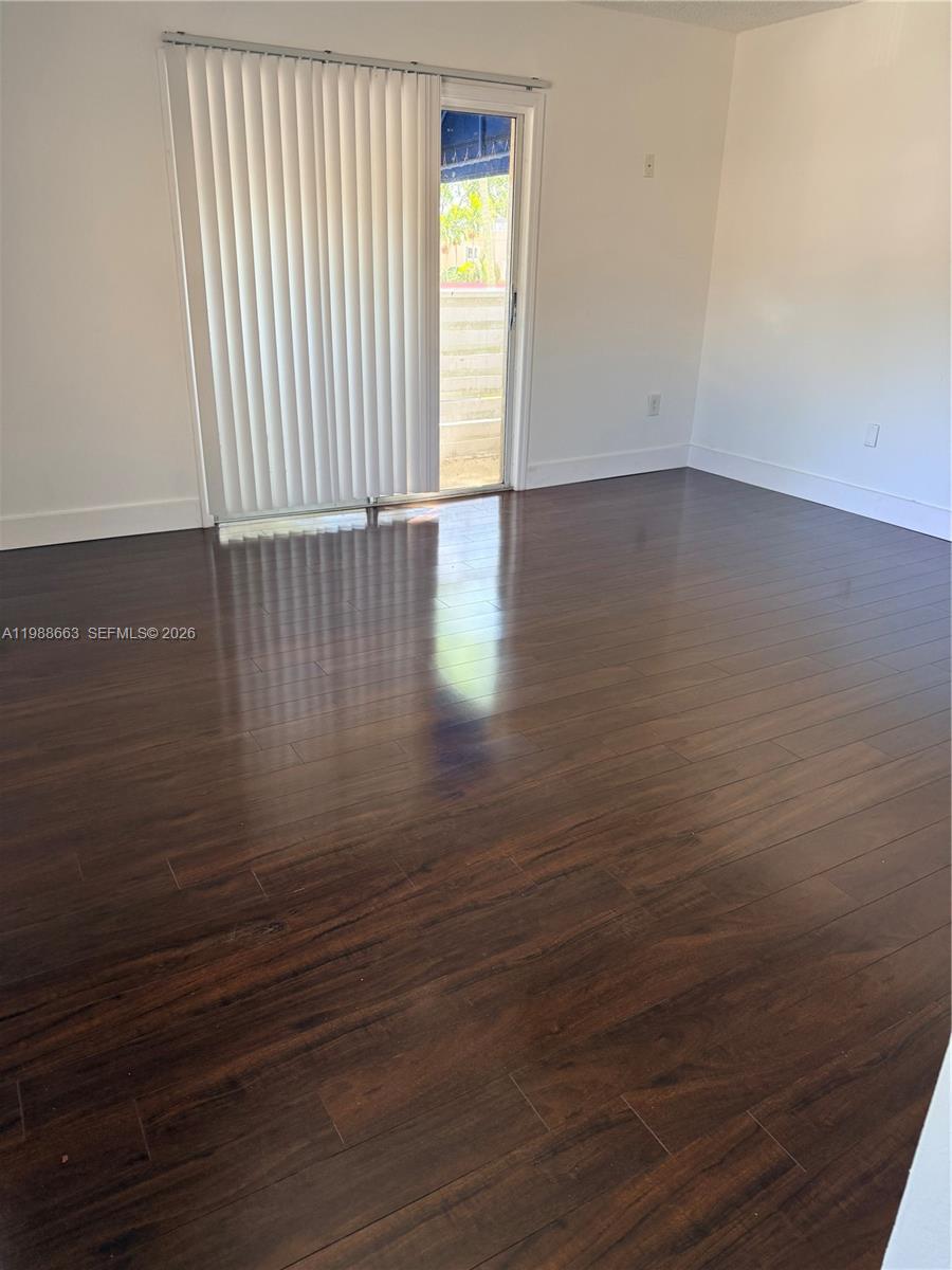 14343 Southwest 98th Terrace Miami, FL 33186 - Photo 10 of 16 an empty room with wooden floor and windows with curtains