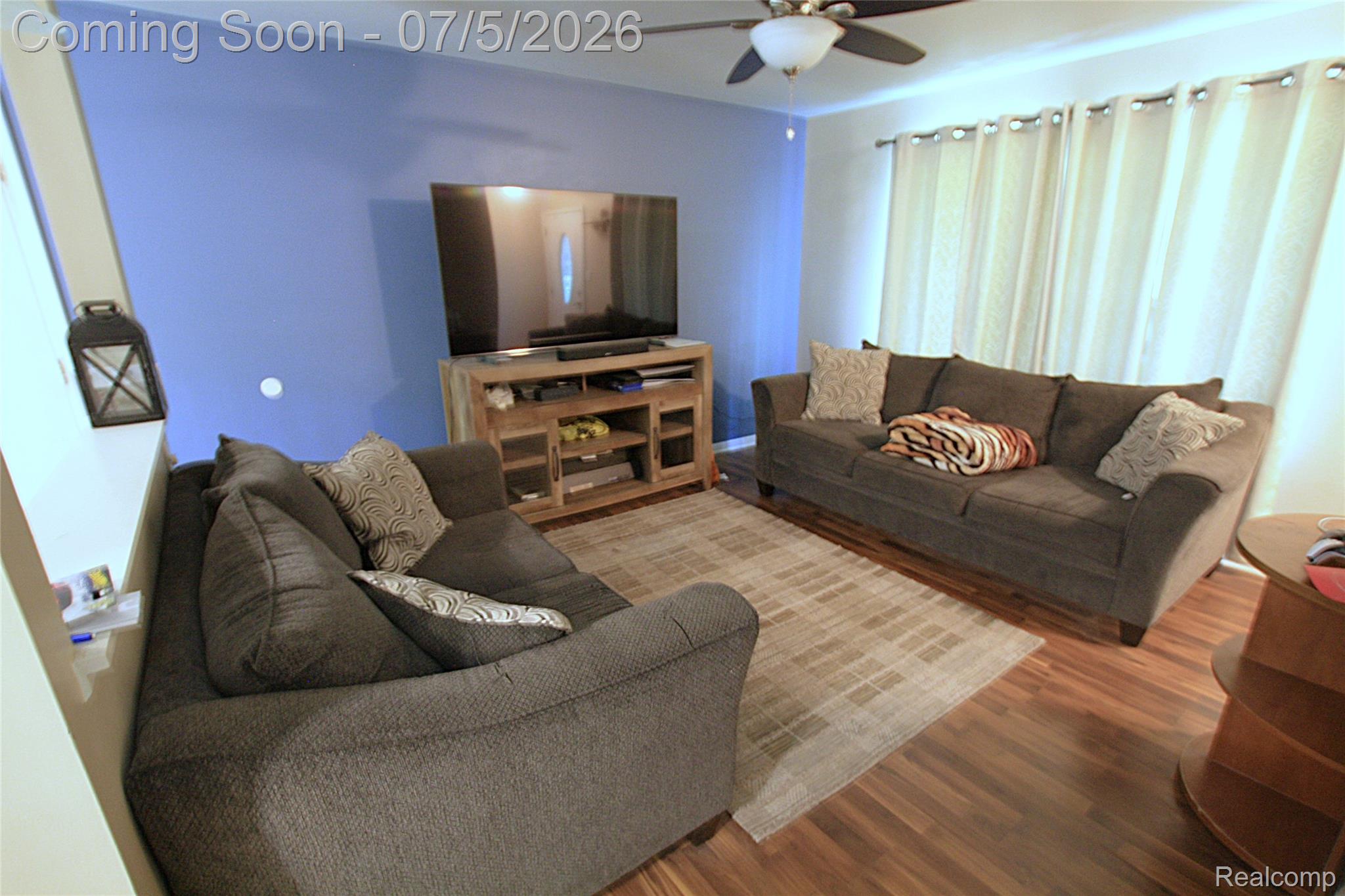 12403 Willard Road Montrose, MI 48457 - Photo 30 of 30 Open living area featuring wood-finish flooring, a ceiling fan, and a window with curtain rods