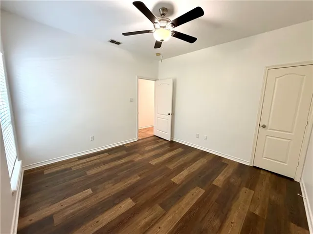 an empty room with wooden floor and ceiling fan