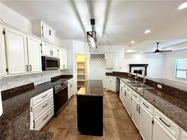 a large kitchen with stainless steel appliances granite countertop a stove a sink and a microwave