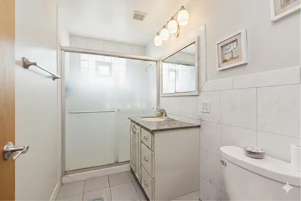 a bathroom with a granite countertop sink a toilet and a shower