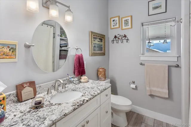 a bathroom with a granite countertop toilet sink and mirror