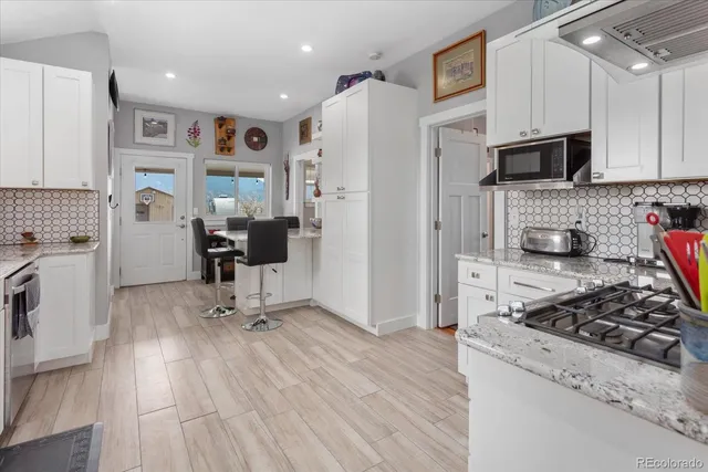 a kitchen with stainless steel appliances a stove a refrigerator a sink dishwasher and a refrigerator with wooden floor