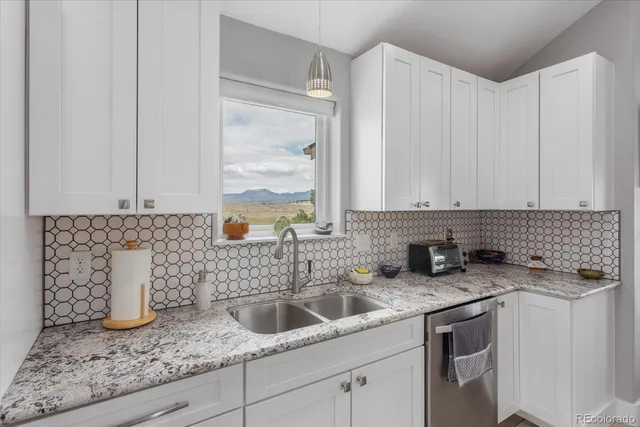 a kitchen with granite countertop white cabinets and a sink