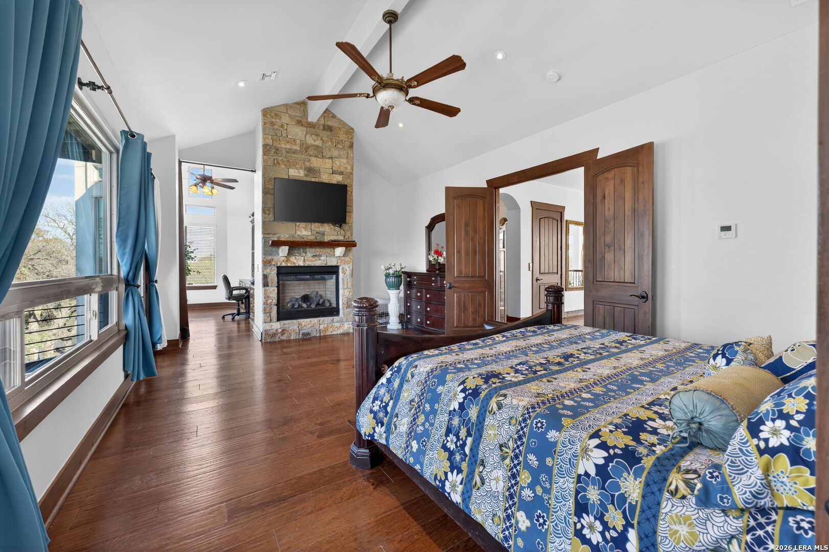 134 Bandit Beach Road New Braunfels, TX 78130 - Photo 33 of 77 a bedroom with a large bed a flat tv screen and a fireplace