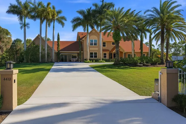 a front view of a house with palm trees