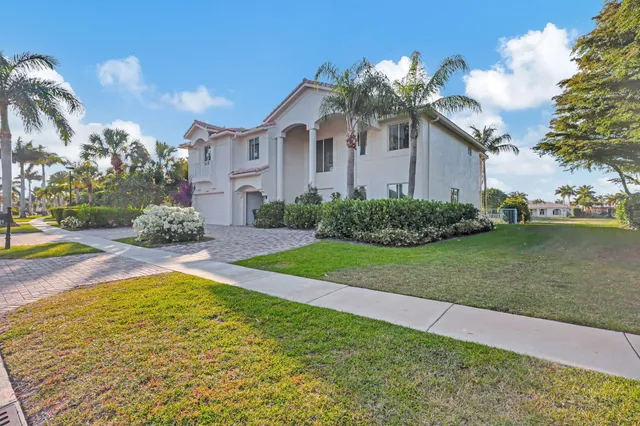 a front view of a house with a yard and palm trees