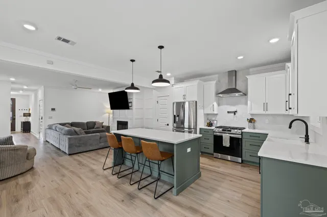 a dining hall with stainless steel appliances granite countertop a refrigerator a sink dishwasher a dining table and chairs with wooden floor