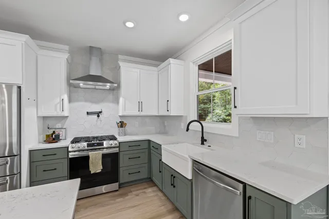 a kitchen with stainless steel appliances a sink a stove center island a window and cabinets