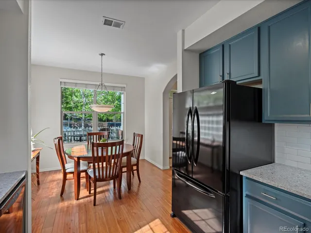 a kitchen with stainless steel appliances a dining table chairs refrigerator and microwave