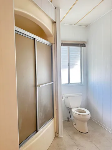 a bathroom with a toilet and a glass door shower
