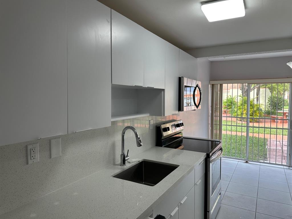9331 Southwest 4th Street, Unit 104B Miami, FL 33174 - Photo 4 of 11 a kitchen with a sink and a refrigerator