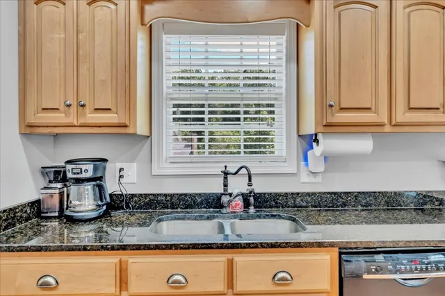 a kitchen with granite countertop a sink a stove and cabinets